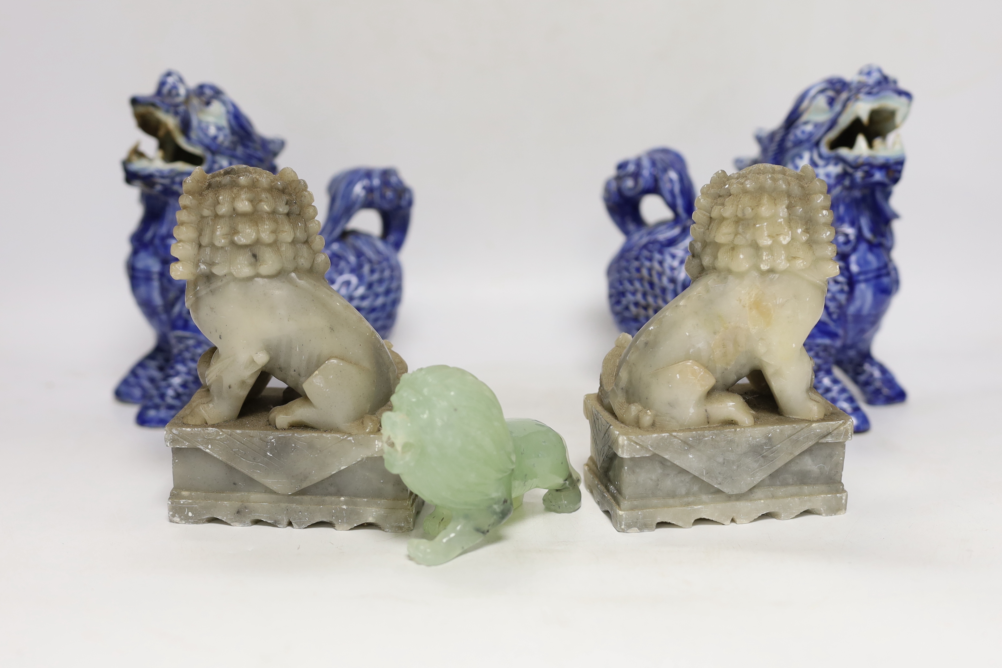 Two pairs of Chinese lion dogs; a blue and white porcelain set and a carved soapstone set, together with a carved jade lion, tallest 18cm (5)